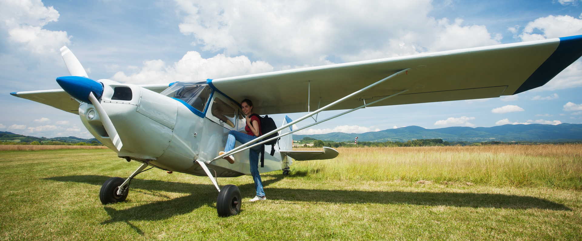 Woman entering small airplane in a grassy field